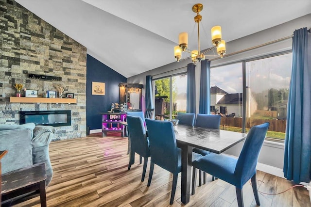 724 Colorado Ct Unit 724, Carol Stream, IL 60188 - dining space featuring a chandelier, vaulted ceiling, wood finished floors, and a stone fireplace
