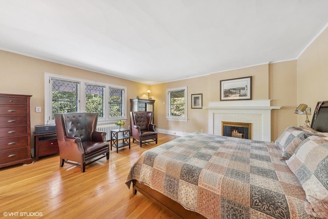 710 W Downer Pl, Aurora, IL 60506 - bedroom with light wood-type flooring, radiator heating unit, and a brick fireplace