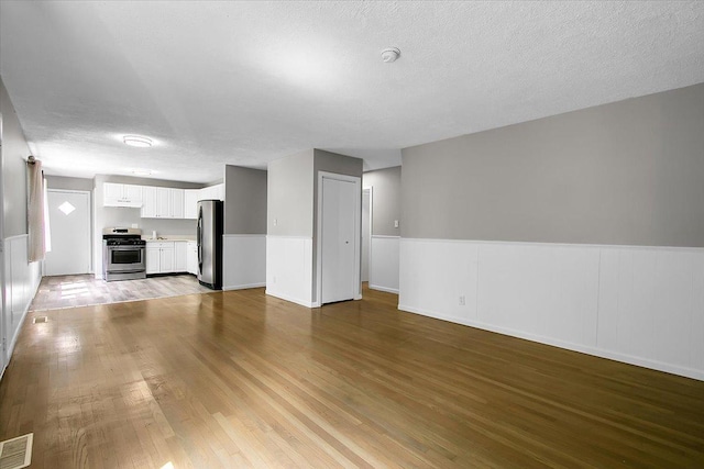 22255 Merrill Ave, Sauk Village, IL 60411 - unfurnished living room featuring wood finished floors, wainscoting, and a textured ceiling