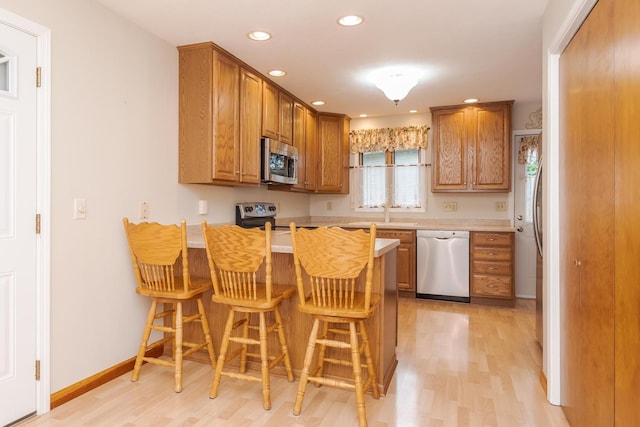 1316 Kirkwood Dr, Pontiac, IL 61764 - kitchen featuring appliances with stainless steel finishes, a peninsula, light wood-type flooring, light countertops, and recessed lighting