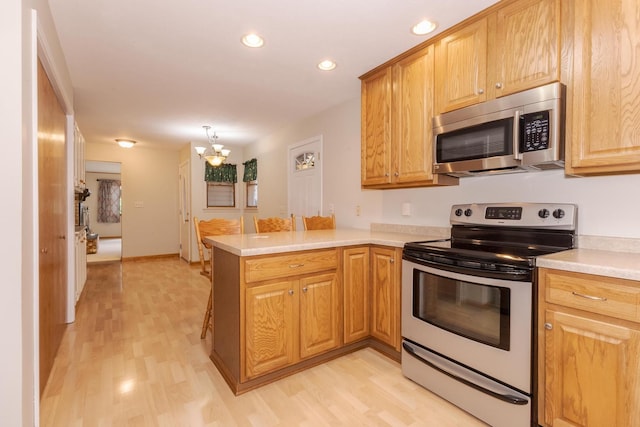 1316 Kirkwood Dr, Pontiac, IL 61764 - kitchen featuring appliances with stainless steel finishes, a peninsula, light wood-type flooring, a chandelier, and light countertops
