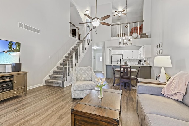 323 Vista Ct Unit C, Minooka, IL 60447 - living room with stairway, a high ceiling, light wood-style floors, ceiling fan, and a chandelier