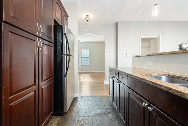 7438 N Hermitage Ave Unit 1E, Chicago, IL 60626 - kitchen with freestanding refrigerator, arched walkways, stone tile floors, light stone countertops, and decorative light fixtures
