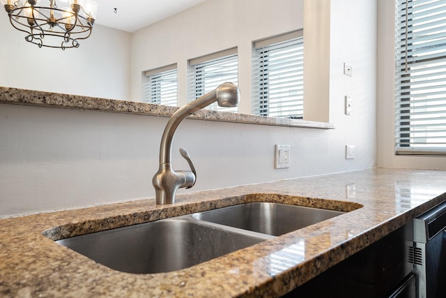7438 N Hermitage Ave Unit 1E, Chicago, IL 60626 - kitchen view of light stone countertops, a chandelier, hanging light fixtures, and dishwashing machine