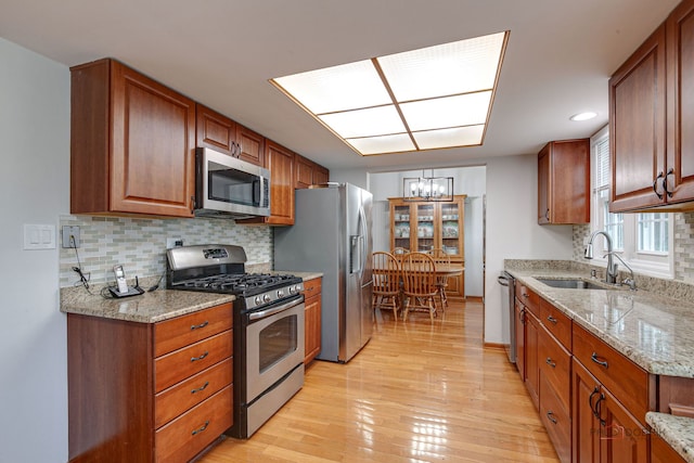 4900 Dukesberry Ln, Hoffman Estates, IL 60010 - kitchen featuring stainless steel appliances, a chandelier, light wood-style flooring, decorative backsplash, and light stone counters