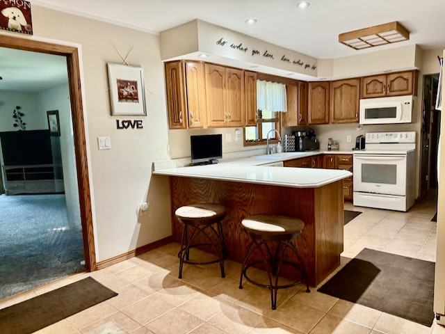 241 E Porter St, Oglesby, IL 61348 - kitchen featuring white appliances, light countertops, a peninsula, a breakfast bar, and recessed lighting