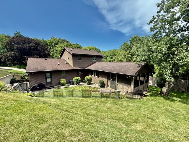 241 E Porter St, Oglesby, IL 61348 - back of property with a fenced backyard, stone siding, a sunroom, and roof with shingles
