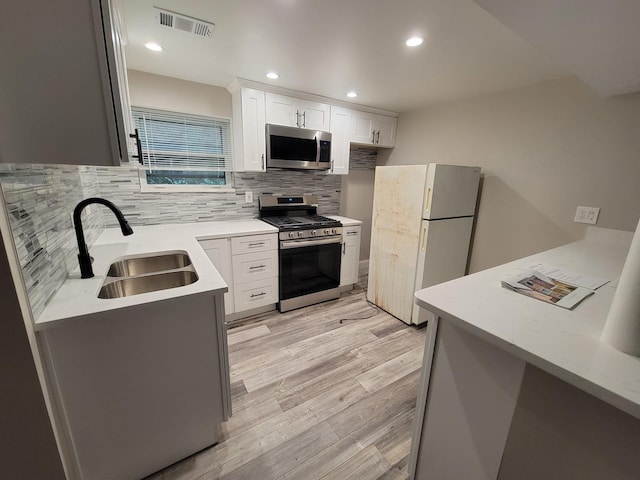 5063 N Menard Ave, Chicago, IL 60630 - kitchen with stainless steel appliances, tasteful backsplash, light countertops, light wood-style flooring, and white cabinetry