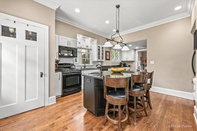 558 W Downer Pl, Aurora, IL 60506 - kitchen with black appliances, ornamental molding, an island with sink, white cabinets, and a breakfast bar