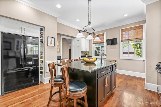 558 W Downer Pl, Aurora, IL 60506 - kitchen featuring freestanding refrigerator, crown molding, white cabinets, light wood finished floors, and a kitchen island with sink