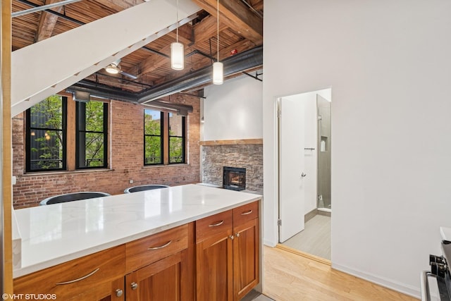 331 S Peoria St Unit Ph6, Chicago, IL 60607 - kitchen featuring a wooden ceiling with exposed beams, brown cabinetry, hanging light fixtures, light wood-style flooring, and a fireplace