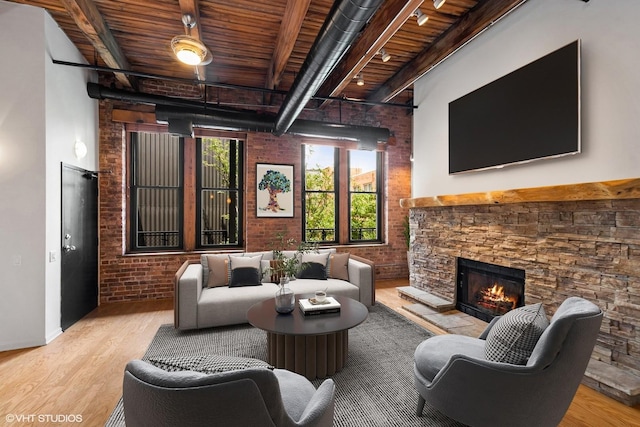 331 S Peoria St Unit Ph6, Chicago, IL 60607 - living area featuring brick wall, a wood ceiling with exposed beams, wood finished floors, a stone fireplace, and a high ceiling