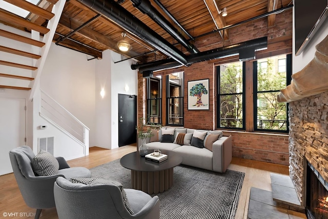 331 S Peoria St Unit Ph6, Chicago, IL 60607 - living area with stairway, brick wall, wood finished floors, a stone fireplace, and a wood ceiling with exposed beams