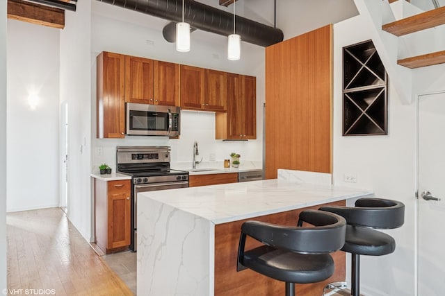 331 S Peoria St Unit Ph6, Chicago, IL 60607 - kitchen featuring stainless steel appliances, brown cabinetry, a towering ceiling, light stone countertops, and pendant lighting