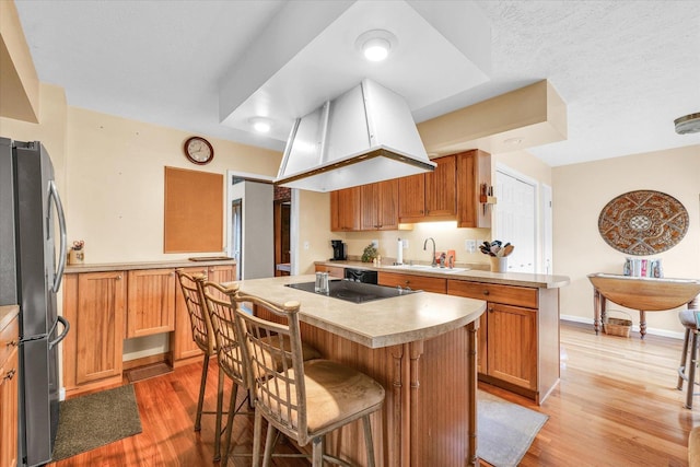 13809 Pine Rd, Dewitt, IL 61735 - kitchen featuring freestanding refrigerator, black electric stovetop, light wood-style floors, a kitchen island, and a breakfast bar area