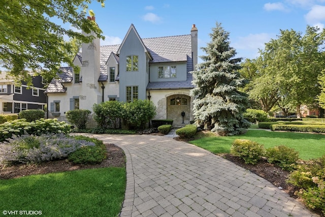 437 N County Line Rd, Hinsdale, IL 60521 - tudor house with a chimney, a high end roof, stone siding, a front lawn, and stucco siding