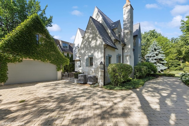 437 N County Line Rd, Hinsdale, IL 60521 - view of property exterior featuring stucco siding, a garage, and a chimney