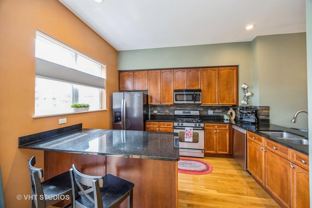 108 Belvidere Ave, Forest Park, IL 60130 - kitchen with appliances with stainless steel finishes, a peninsula, light wood finished floors, decorative backsplash, and a breakfast bar area
