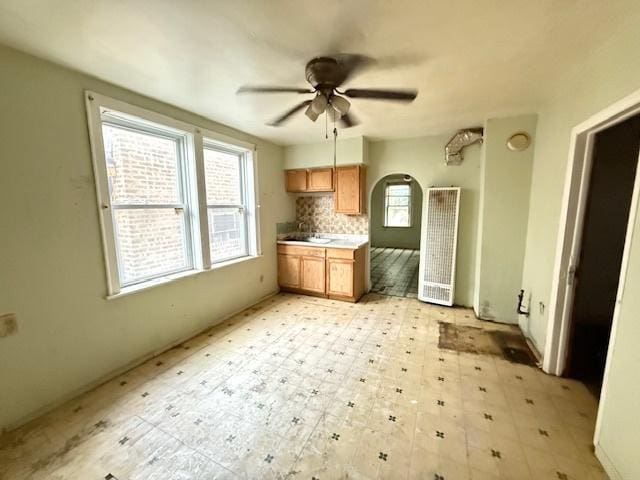 4904 W 31st St, Cicero, IL 60804 - kitchen featuring a ceiling fan, tasteful backsplash, brown cabinetry, arched walkways, and light countertops