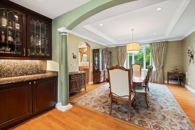 3550 Sorrel Dr, Northbrook, IL 60062 - dining area featuring ornate columns, arched walkways, light wood-style flooring, a tray ceiling, and crown molding