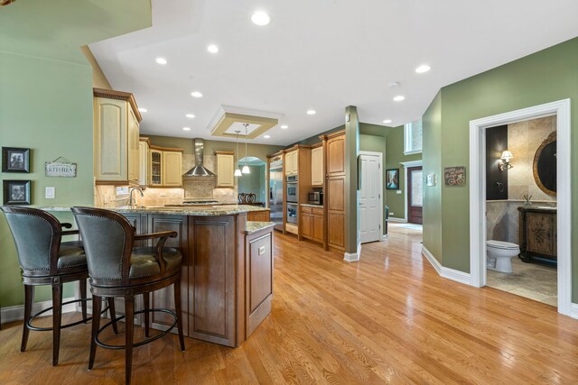 3550 Sorrel Dr, Northbrook, IL 60062 - kitchen featuring wall chimney exhaust hood, a peninsula, light wood-style flooring, glass insert cabinets, and recessed lighting