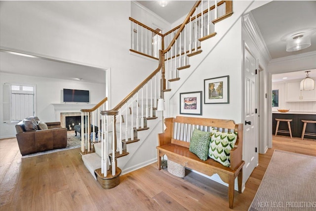 1412 Sherwood Ln, Geneva, IL 60134 - staircase with ornamental molding, wood finished floors, a fireplace, and a towering ceiling