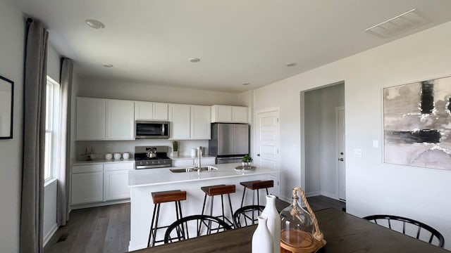 998 Amethyst Ln, Montgomery, IL 60538 - kitchen featuring stainless steel appliances, white cabinetry, a breakfast bar, light countertops, and dark wood finished floors