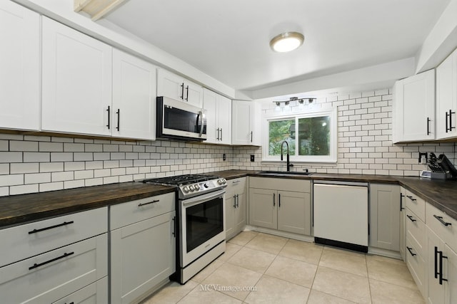 204 Wood St, Wilmington, IL 60481 - kitchen with stainless steel appliances, butcher block countertops, tasteful backsplash, light tile patterned floors, and white cabinetry