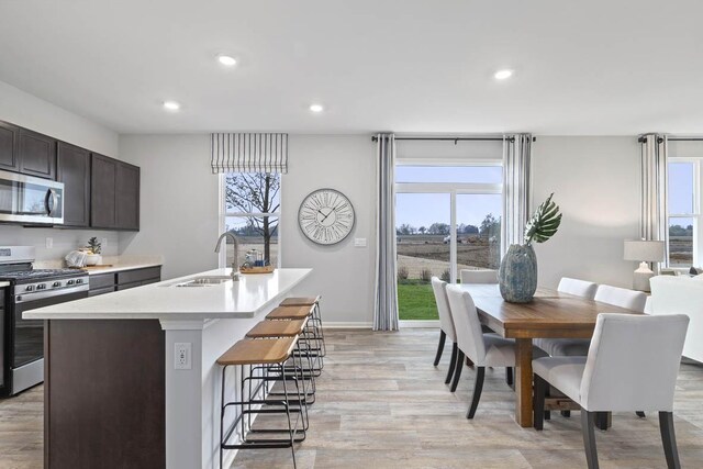 994 Amethyst Ln, Montgomery, IL 60538 - kitchen featuring appliances with stainless steel finishes, light wood-type flooring, a center island with sink, light countertops, and a kitchen breakfast bar