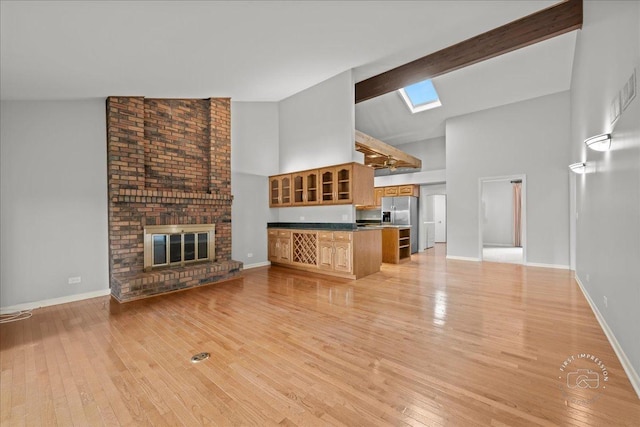1105 W Bauer Rd, Naperville, IL 60563 - unfurnished living room with high vaulted ceiling, a skylight, light wood finished floors, and a brick fireplace