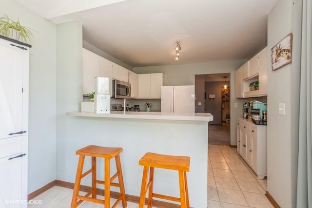 2261 Petworth Ct Unit 201C, Naperville, IL 60565 - kitchen with stainless steel microwave, freestanding refrigerator, a peninsula, light countertops, and light tile patterned flooring