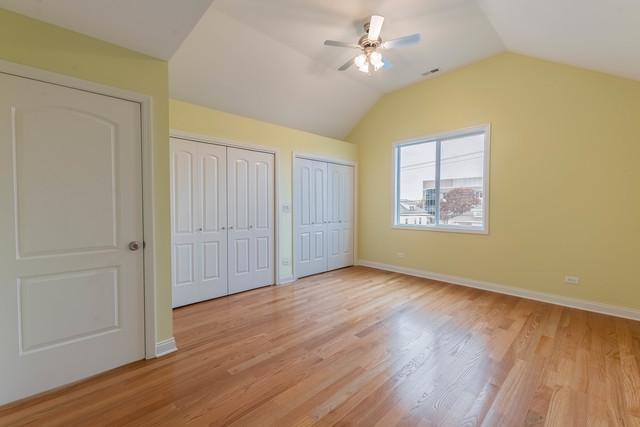 5326 W 31st St, Cicero, IL 60804 - unfurnished bedroom featuring two closets, light wood finished floors, lofted ceiling, and ceiling fan