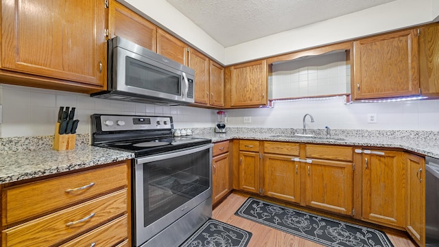 5715 Elaine Dr, Rockford, IL 61108 - kitchen with appliances with stainless steel finishes, decorative backsplash, brown cabinets, light wood-type flooring, and light stone counters