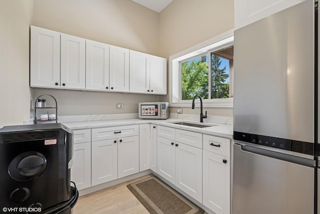 2104 Shermer Rd, Northbrook, IL 60062 - kitchen featuring freestanding refrigerator, white cabinetry, light wood-style floors, and light stone countertops