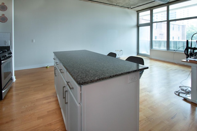 50 E 16th St Unit 311, Chicago, IL 60616 - kitchen with stainless steel stove, light wood-type flooring, a kitchen island, and white cabinets