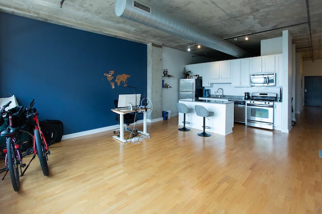50 E 16th St Unit 311, Chicago, IL 60616 - kitchen with stainless steel appliances, light wood finished floors, a kitchen breakfast bar, white cabinets, and a center island