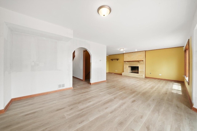 3057 201st Pl, Lynwood, IL 60411 - unfurnished living room featuring light wood finished floors, arched walkways, and a fireplace