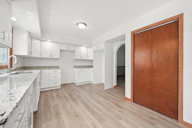 3057 201st Pl, Lynwood, IL 60411 - kitchen with light stone countertops, light wood-type flooring, arched walkways, and white cabinetry