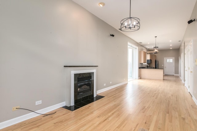 2901 W Washington Blvd Unit 2, Chicago, IL 60612 - unfurnished living room with a chandelier, light wood-style flooring, a tiled fireplace, and recessed lighting