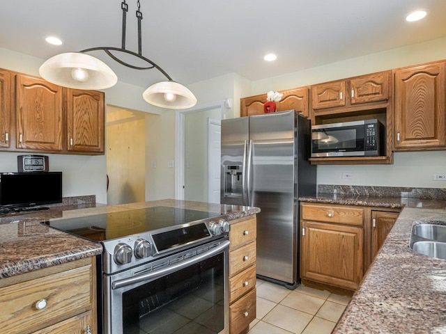 18036 Crystal Ln, Lansing, IL 60438 - kitchen with stainless steel appliances, light tile patterned floors, brown cabinetry, dark stone counters, and decorative light fixtures