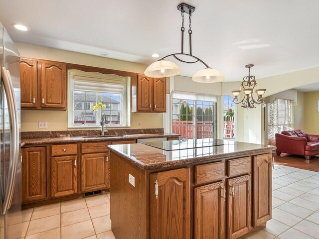 18036 Crystal Ln, Lansing, IL 60438 - kitchen featuring stainless steel refrigerator, light tile patterned floors, a kitchen island, black electric cooktop, and brown cabinetry