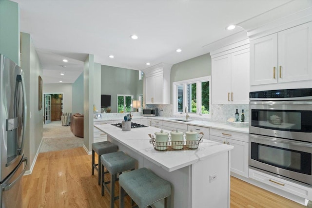 7488 Bittersweet Dr, Gurnee, IL 60031 - kitchen featuring stainless steel appliances, a breakfast bar, light wood-style floors, white cabinetry, and backsplash