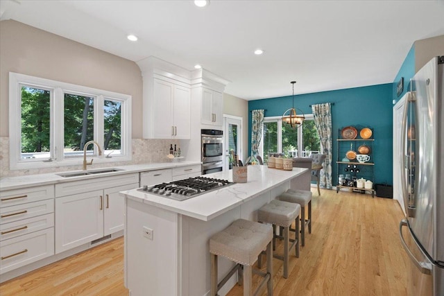 7488 Bittersweet Dr, Gurnee, IL 60031 - kitchen with appliances with stainless steel finishes, light wood-style floors, white cabinetry, backsplash, and a breakfast bar area