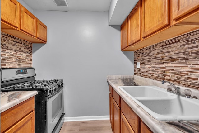 6 E Dundee Quarter Dr Unit 101, Palatine, IL 60074 - kitchen featuring stainless steel range with gas cooktop, decorative backsplash, light wood-style floors, brown cabinets, and light countertops