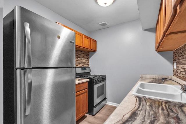 6 E Dundee Quarter Dr Unit 101, Palatine, IL 60074 - kitchen with stainless steel appliances, tasteful backsplash, brown cabinetry, and light wood-style floors