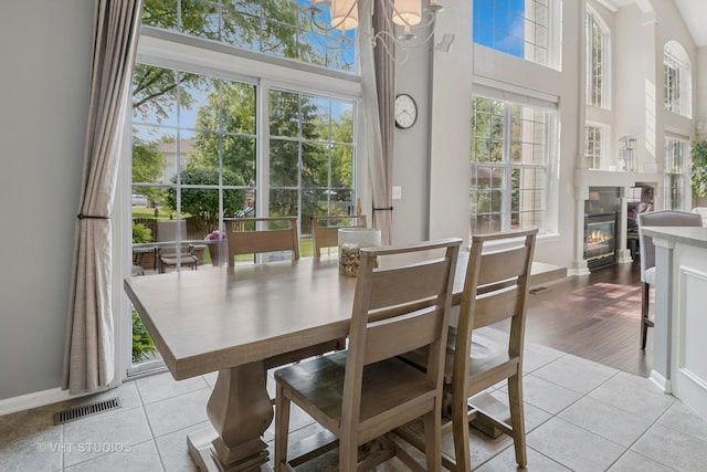 424 Bluegrass Ln, Geneva, IL 60134 - dining area featuring healthy amount of natural light, light tile patterned floors, a towering ceiling, and a glass covered fireplace