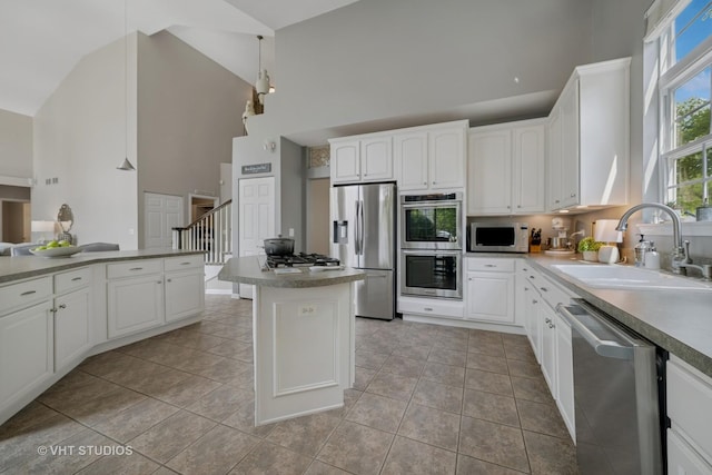 424 Bluegrass Ln, Geneva, IL 60134 - kitchen featuring appliances with stainless steel finishes, high vaulted ceiling, white cabinets, a kitchen island, and light tile patterned floors