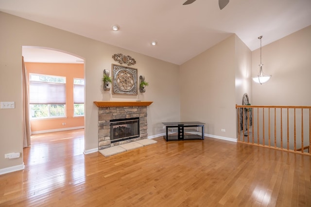 424 Riverbend Dr, Genoa, IL 60135 - living area featuring a ceiling fan, wood finished floors, vaulted ceiling, arched walkways, and a stone fireplace