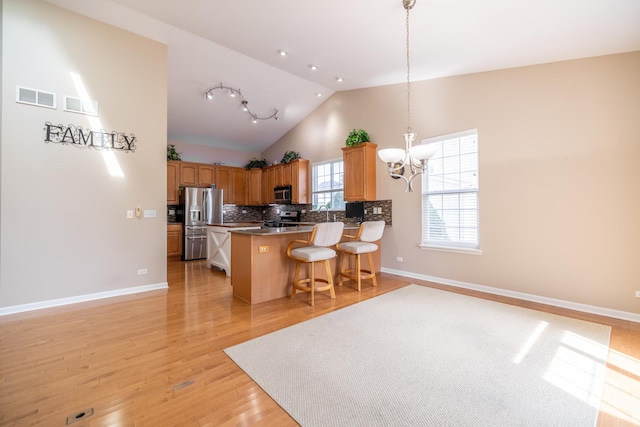 424 Riverbend Dr, Genoa, IL 60135 - kitchen with appliances with stainless steel finishes, a chandelier, a kitchen bar, lofted ceiling, and a peninsula