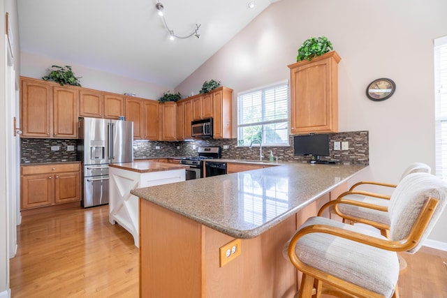 424 Riverbend Dr, Genoa, IL 60135 - kitchen featuring appliances with stainless steel finishes, a breakfast bar, a peninsula, light wood-style flooring, and a center island